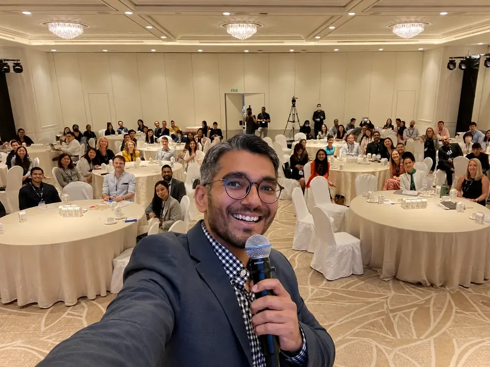 Dhawal Shah leading a packed AI marketing training session, mic in hand, a full room of learners behind him.